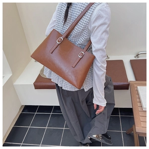 Brown oil-wax leather tote bag detail with adjustable shoulder straps and silver buckles
