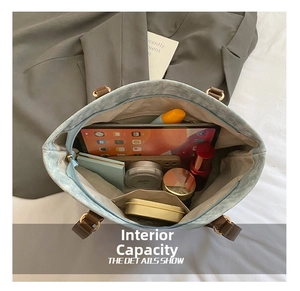 Detail showing the spacious interior of a blue denim tote bag with leather handles