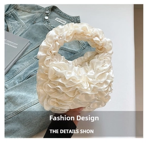 Detail of white ruffled bag with pleated satin texture shown with denim jacket