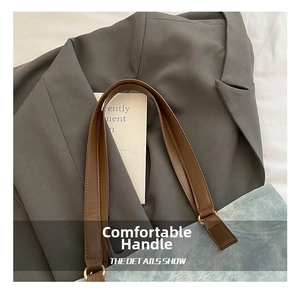 Detail of brown faux leather handle with metal rings on a blue canvas tote bag