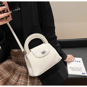 Detail of white pleated handbag with silver twist lock and adjustable crossbody strap