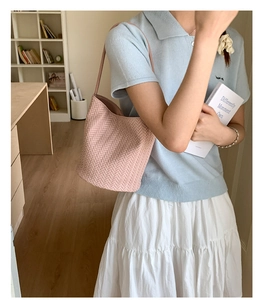 Detail of light pink woven bucket bag with herringbone texture and shoulder strap