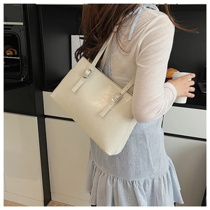 Chic white leather tote bag with double metal buckle straps shown on a female model