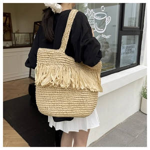 Detail of hand-woven straw tote bag with long fringe tassels for summer beach vacation