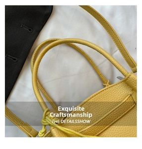 Close-up of yellow lychee grain leather bucket bag with fine stitching and round handle