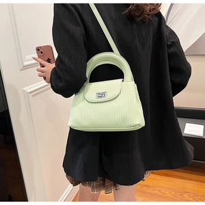 Detail of mint green striped crossbody bag with silver rotating lock on a black blazer