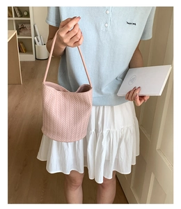 Detailed view of pink woven bucket bag with herringbone texture in lifestyle setting