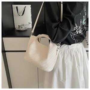 Close-up of cream woven bucket bag showing fine twill texture and dual strap design
