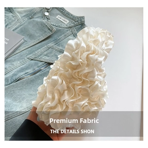 Close-up of white ruffled fabric with silk-like texture and glossy pleated details