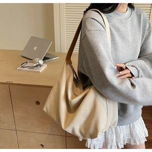 Dettaglio della borsa tote in tela beige con tracolla in pelle marrone in un ufficio
