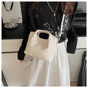 Detail of cream woven leather bucket bag with silver metal hooks and adjustable strap