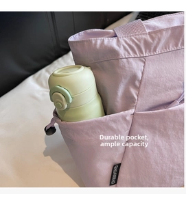 Detail of the side pocket on a lavender canvas tote bag holding a water bottle