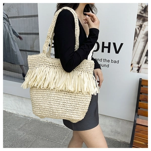 Detail of bohemian woven tote bag featuring long fringes and textured cream straw material