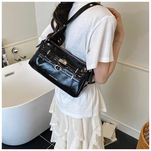 Nahaufnahme einer schwarzen Lack-Achseltasche mit Silberschnalle und modischem Schriftdetail