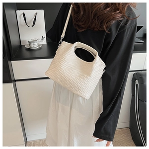 Detailed side view of white woven handbag with intricate V-pattern texture and strap
