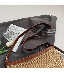 Detail of woven straw shoulder bag with brown leather strap and silver metal ring connector