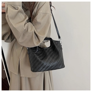 Close-up of black herringbone woven texture handbag with sleek leather shoulder strap