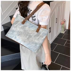 Detail of light blue marbled tote bag featuring brown leather straps and gold metal rings