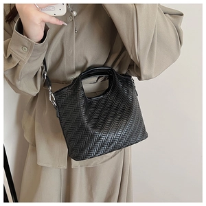 Close-up of black woven leather tote bag with circular handle and detachable strap