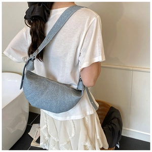 Detail of grey croissant shoulder bag with pleated texture and knotted strap design