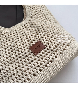 Close-up of beige crochet shoulder bag showing intricate hollow weave and leather logo patch