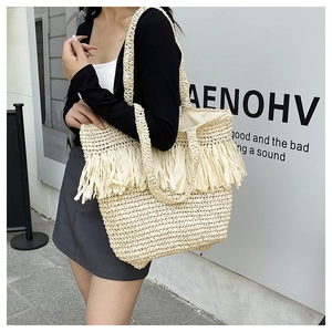 Detailed close-up of handmade woven straw tote bag with long decorative fringe accents