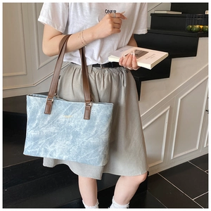 Close-up of marble texture blue tote bag with brown leather handles and gold metal accents
