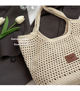 Detail of hollow knit cotton tote with brown leather brand tag and beige mesh texture