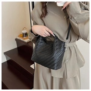 Detail of black woven bucket bag with fine leather texture and silver metal hardware