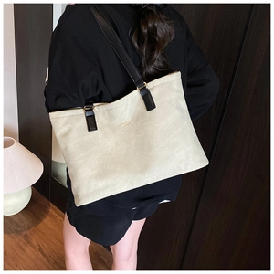 Detail of minimalist cream tote bag showing soft leather texture and long black straps