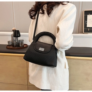 Detail view of black leather bucket bag with pleated texture and silver twist lock closure