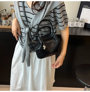 Detail of black lychee grain leather bucket bag with silver charm and double handles