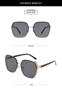 Detail view of large geometric black grey sunglasses with hollow golden metal frame