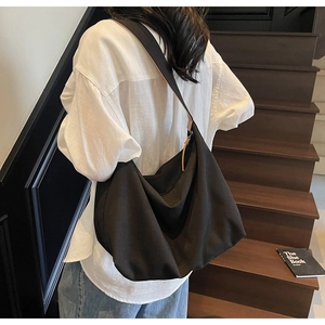 Dettaglio della borsa hobo in tela nera a spalla, che mostra il drappeggio morbido e lo stile