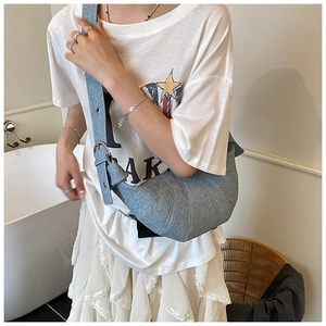 Detail of light blue crescent bag showing denim texture and adjustable silver buckle