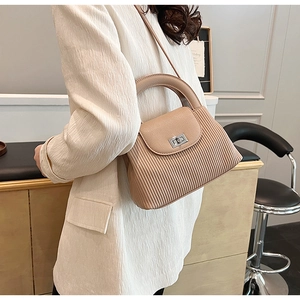 Close-up of beige pleated bucket bag with silver metal twist lock and shoulder strap