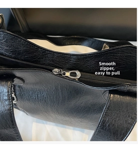 Detailed view of the smooth silver metal zipper and black leather texture on a tote bag