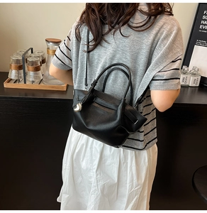 Detail of black lychee grain leather bucket bag with silver heart pendant and shoulder strap