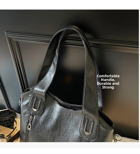 Close-up of a black tote bag showing shiny leather texture and silver metal hardware