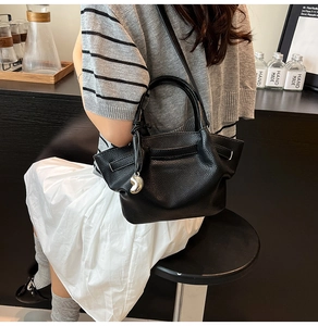 Close-up of black litchi grain leather bucket bag with silver metal pendant detail
