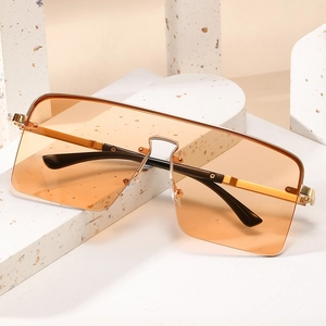 Lunettes de soleil carrées en métal avec verres orange sur un socle en pierre
