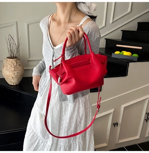 Detail of red lychee pattern leather bucket bag with silver charm and top handle