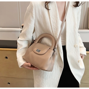 Detail of elegant beige quilted crossbody bag with silver metal buckle and top handle