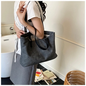 Charcoal grey large tote bag with wide black leather straps shown on shoulder of a model