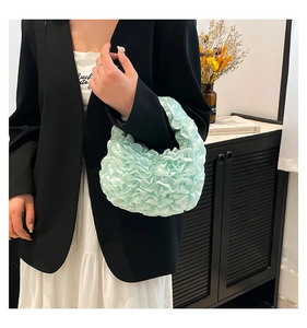 Detail of mint green pleated satin handbag with ruffled lace texture and elegant finish