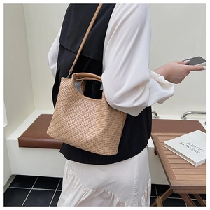 Detail of hand-woven beige tote bag with intricate texture and detachable shoulder strap