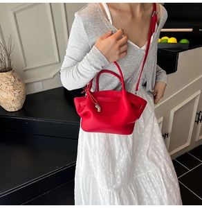 Detail of red bucket bag with lychee texture, folding structure and silver charm