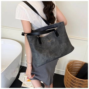 Detail of charcoal grey matte leather tote bag with gold lettering and black straps