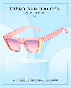 Cat eye sunglasses with pink gradient lenses and gold metal accents on blue background