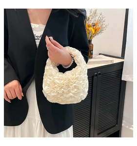 Detailed view of cream ruffled satin cloud handbag with layered lace design and soft texture